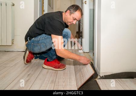 Uomo che lavora con le dita amputate. Sta lavorando alla posa del pavimento in casa sua durante il giorno. Foto Stock