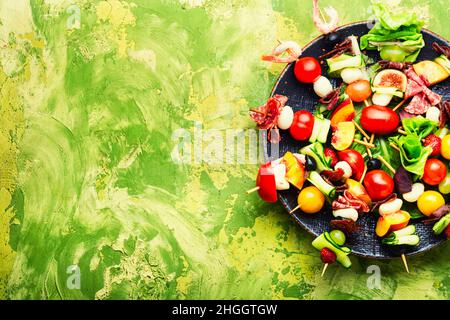 Spuntino festivo di gamberetti, jamon, frutta e verdure su spiedini di legno. Foto Stock