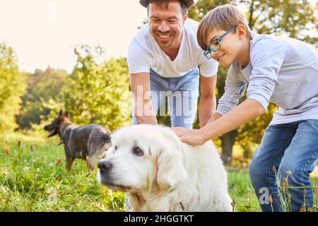 Padre e figlio con due cani in una passeggiata nella natura in estate nel parco Foto Stock