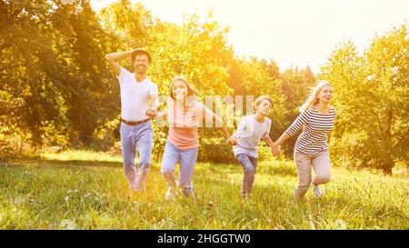 Famiglia con due bambini che tengono le mani mentre si esercitano in giardino in estate Foto Stock