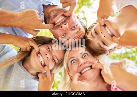 Genitori e bambini si divertono insieme facendo volti e mostrando denti Foto Stock