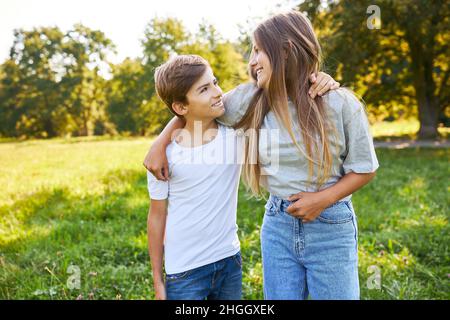 Fratello e sorella come fratelli felici i bambini si abbracciano a vicenda nel parco in estate Foto Stock