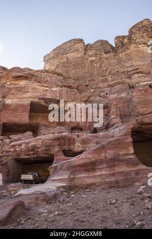 Toyota pick-up camion parcheggiati in antiche strutture Nabatee a Petra, Giordania tra canyon, grotte, paesaggio desertico ed edifici. Foto Stock