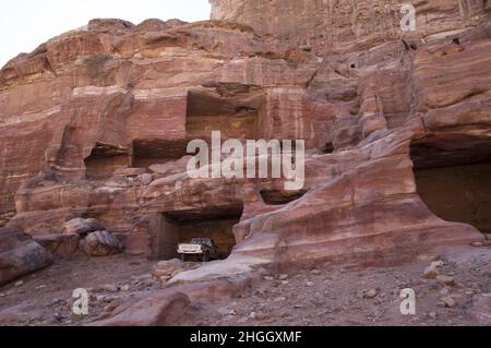 Toyota pick-up camion parcheggiati in antiche strutture Nabatee a Petra, Giordania tra canyon, grotte, paesaggio desertico ed edifici. Foto Stock