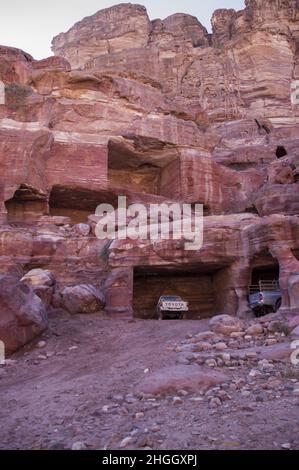 Toyota pick-up camion parcheggiati in antiche strutture Nabatee a Petra, Giordania tra canyon, grotte, paesaggio desertico ed edifici. Foto Stock