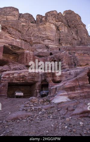 Toyota pick-up camion parcheggiati in antiche strutture Nabatee a Petra, Giordania tra canyon, grotte, paesaggio desertico ed edifici. Foto Stock