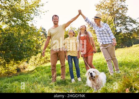 La famiglia con due bambini e un cane si divertono in un'escursione estiva nel parco Foto Stock