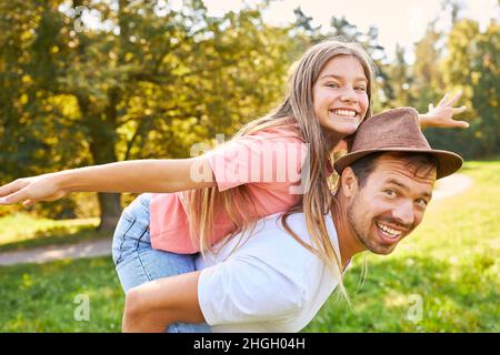 Il padre felice porta la sua figlia allegra piggyback in estate Foto Stock