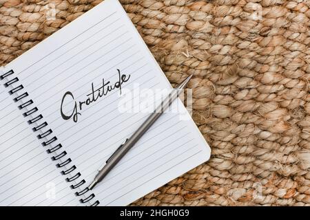 Taccuino con la parola gratitudine scritta su di esso. Posto su una superficie rustica Foto Stock