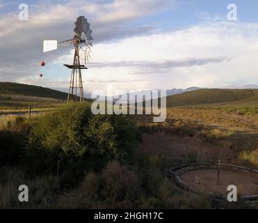 Mulino a vento e pompa d'acqua in paesaggio secco Foto Stock