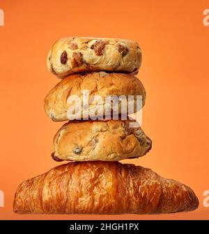 Panini e croissant in un ambiente studio, isolati su arancione. Foto Stock