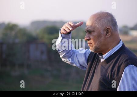 uomo anziano che guarda lontano nel parco Foto Stock