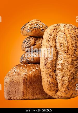 Pane e panini in un ambiente studio isolato su arancione. Foto Stock