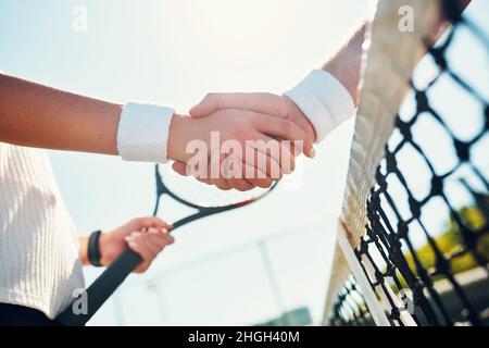 Congratulazioni Champ. Scatto corto di due irriconoscibili giocatori di tennis che si scuotono insieme all'aperto sul campo. Foto Stock