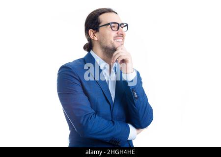 Un uomo d'affari allegro sorridente tiene la mano sotto il mento isolato su sfondo bianco. La persona d'affari contented indossa gli occhiali guardando avanti messo a fuoco, thinki Foto Stock
