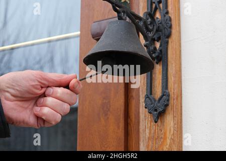Tradizionale vecchia porta campana di metallo per anello su porta di legno. Foto Stock