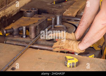 Montaggio di barre di rinforzo per la colata di calcestruzzo. Background industriale. L'operatore sta piegando le barre di armatura con la macchina piegatrice di armatura nel luogo. Foto Stock