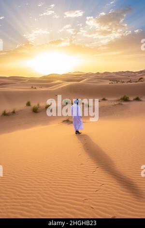 Giovane uomo arabo che indossa abiti berberi tradizionali nel deserto del Sahara di Merzouga, Marocco Foto Stock