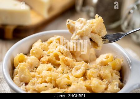 Primo piano di macaroni e formaggio su una forchetta e in una teglia bianca Foto Stock