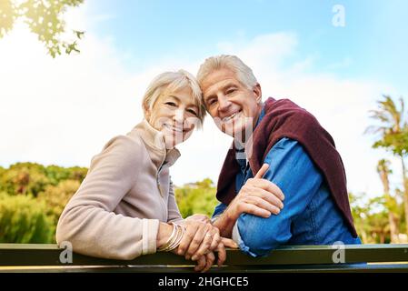 Sono qui giorni più luminosi. Ritratto di una coppia felice seduta su una panchina del parco. Foto Stock