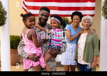 Ritratto di sorridente famiglia afroamericana con soldato militare in piedi all'ingresso della casa Foto Stock