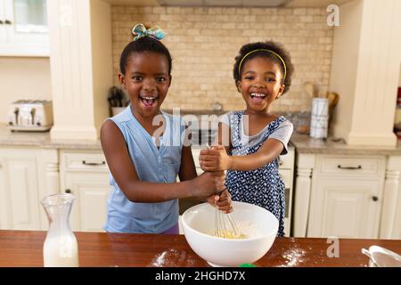 Ritratto di felice due sorelle afroamericane che cucinano insieme in cucina a casa Foto Stock