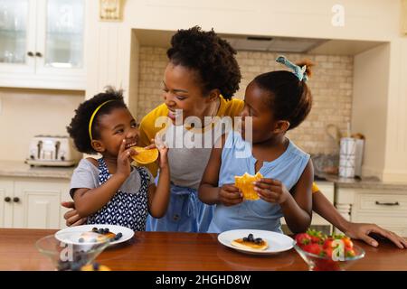 Madre Africana americana e le sue due figlie che hanno fatto colazione in cucina a casa Foto Stock