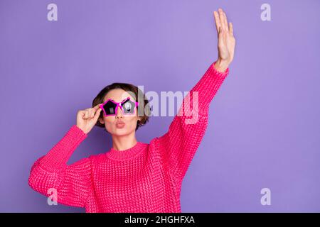 Foto di adorabile signora bacio labbra sollevare braccio palma toccare stella forma vetro solare isolato su sfondo di colore viola Foto Stock