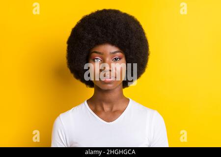 Foto di grave giovane pelle scura donna calma pacifica viso volume capelli isolato su sfondo giallo Foto Stock