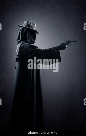 Figura creepy con cappello vecchio e pistola nel buio Foto Stock