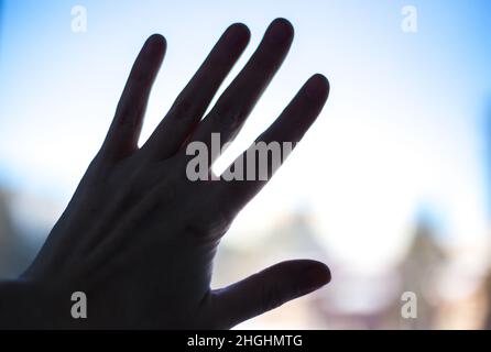 il profilo della mano della donna sul vetro di una finestra di strada Foto Stock