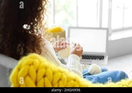 Giovane donna afroamericana che prende le classi di maglieria in linea nel paese Foto Stock