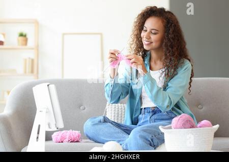 Giovane donna afroamericana che prende le classi di maglieria in linea nel paese Foto Stock