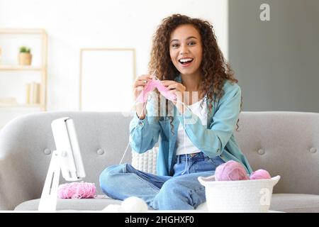 Giovane donna afroamericana che prende le classi di maglieria in linea nel paese Foto Stock