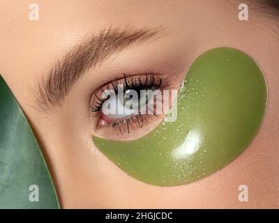 Primo piano dell'occhio della donna con cerotto verde sotto di esso Foto Stock