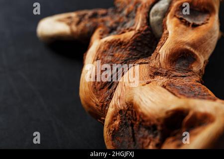 Curva testurizzata legno serpente di colore marrone con texture su sfondo nero. Elemento decorativo in legno, primo piano, minimalismo. Foto Stock