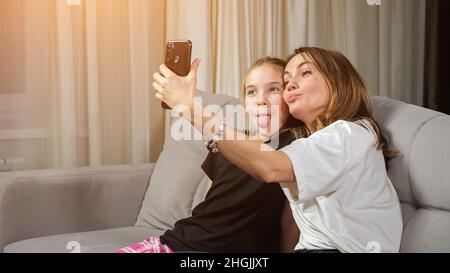 Madre e figlia teen fanno selfie in soggiorno a casa Foto Stock