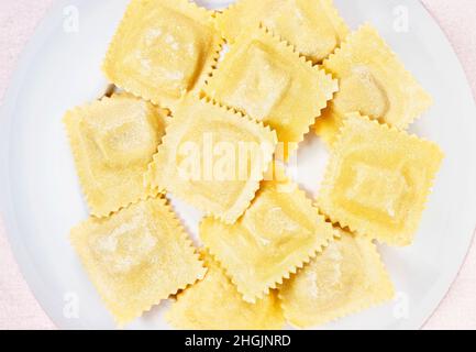 Ravioli quadrati non cotti su piatto bianco Foto Stock