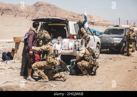 Le forze della coalizione finlandese assistono gli sfollati per il trattamento successivo durante un'evacuazione all'aeroporto internazionale Hamid Karzai, Kabul, Afghanistan, 24 agosto. I membri del servizio degli Stati Uniti e le forze di coalizione stanno assistendo il Dipartimento di Stato con un'operazione di evacuazione non combattente (NEO) in Afghanistan. Foto Stock