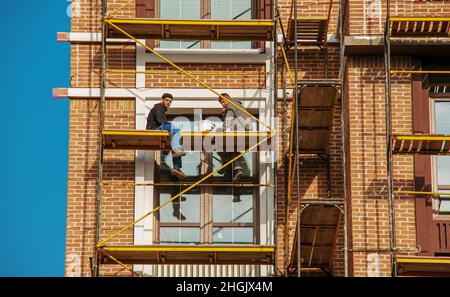 Dnipropetrovsk, Ucraina - 11.22.2021: I costruttori effettuano lavori di finitura della facciata sul ponteggio Foto Stock