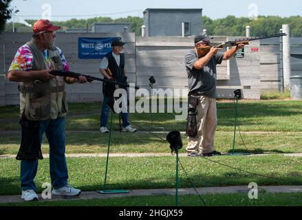 I concorrenti della Retiree Trap League si alternano a sparare a piccioni di argilla il 24 agosto 2021, al Rod and Gun Club sulla base dell'aeronautica militare di Wright-Patterson, Ohio. I microfoni raccolgono il comando di "tirare!" — attivazione della macchina ad attivazione vocale per avviare il disco. Foto Stock