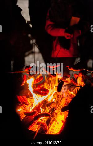 arrostire le salsicce al fuoco in inverno Foto Stock