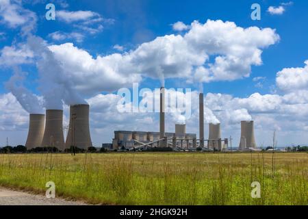 Centrale elettrica funzionante a carbone in Sudafrica. Campo erba in primo piano Foto Stock