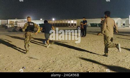 Soldati con la compagnia militare di polizia 127th, 759th MP Battaglione, 89th MP Brigade, giocare a calcio con gli evacuati afghani su una base militare degli Stati Uniti in Kuwait 30 agosto 2021. Poiché il processo di verifica per ciascuna famiglia ha richiesto diversi giorni, è stato importante mantenere gli immigrati in alto spirito durante questo periodo. Foto Stock