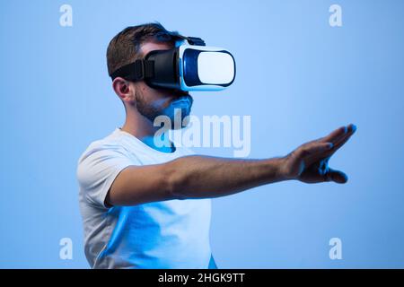 Uomo europeo in occhiali VR al neon. Concetto di gadget e tecnologie moderne. VR, AR, MR, XR- tecnologia futura. Foto Stock