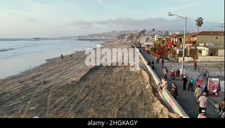 Vista aerea lungo la passerella mentre la folla si riunisce per guardare il tramonto dorato, in bicicletta, jogging, o a piedi a Pacific Beach a San Diego, California, Stati Uniti Foto Stock