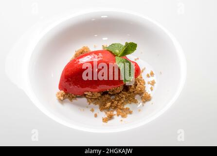 Gelato artigianale biologico sorbetto al Berry Quenelle a forma di foglie di menta su biscotti sbriciolati Foto Stock