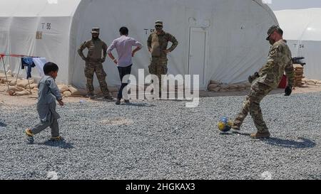 Soldati con la compagnia militare di polizia 127th, 759th MP Battaglione, 89th MP Brigade, giocare a calcio con gli evacuati afghani su una base militare degli Stati Uniti in Kuwait 31 agosto 2021. Poiché il processo di verifica per ciascuna famiglia ha richiesto diversi giorni, è stato importante mantenere gli immigrati in alto spirito durante questo periodo. Foto Stock