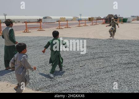 Soldati con la compagnia militare di polizia 127th, 759th MP Battaglione, 89th MP Brigade, giocare a calcio con gli evacuati afghani su una base militare degli Stati Uniti in Kuwait 31 agosto 2021. Poiché il processo di verifica per ciascuna famiglia ha richiesto diversi giorni, è stato importante mantenere gli immigrati in alto spirito durante questo periodo. Foto Stock