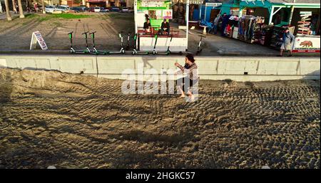 Vista aerea sopra il slackliner maschile bilanciamento su corda e fare acrobazie, adiacente al lungomare su Pacific Beach a San Diego, California, Stati Uniti Foto Stock